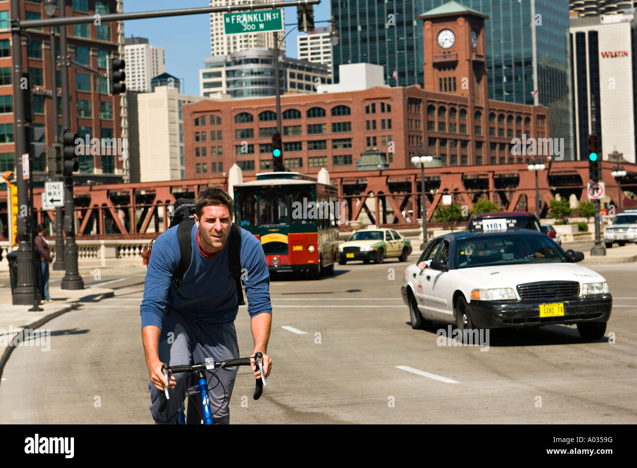 ILLINOIS Chicago uomo guidare la bicicletta senza casco su Wacker Drive occupato carreggiata in tram per il centro e il traffico dei veicoli Foto Stock