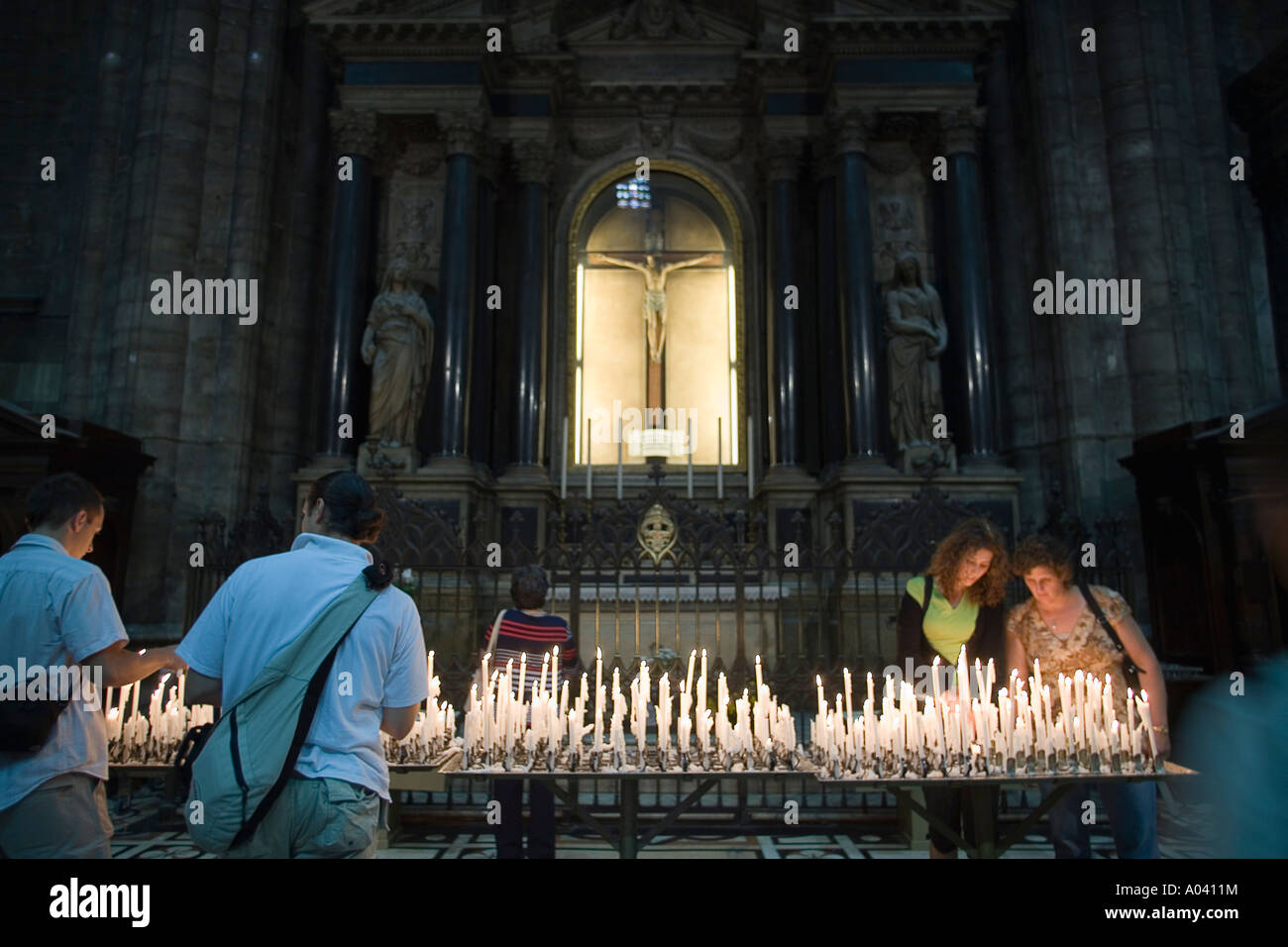 Persone posizionare le candele accese nella cremagliera in un altare laterale al Duomo Milano Italia Foto Stock