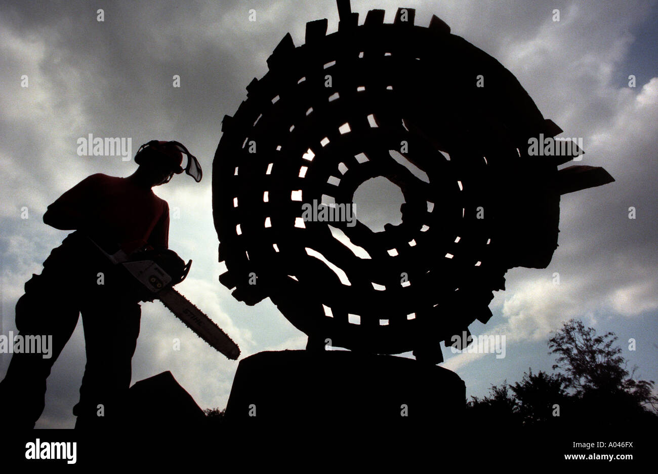 Legno riciclato trasformato in scultura di uomo in elmetto con chainsaw. Foto Stock