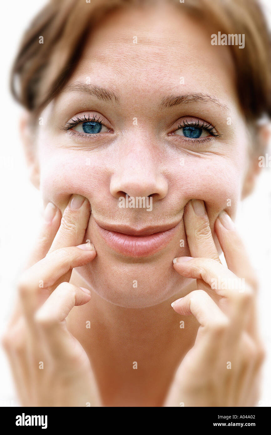 Ritratto di giovane donna spingendo fino agli angoli della sua bocca per forza un sorriso Foto Stock