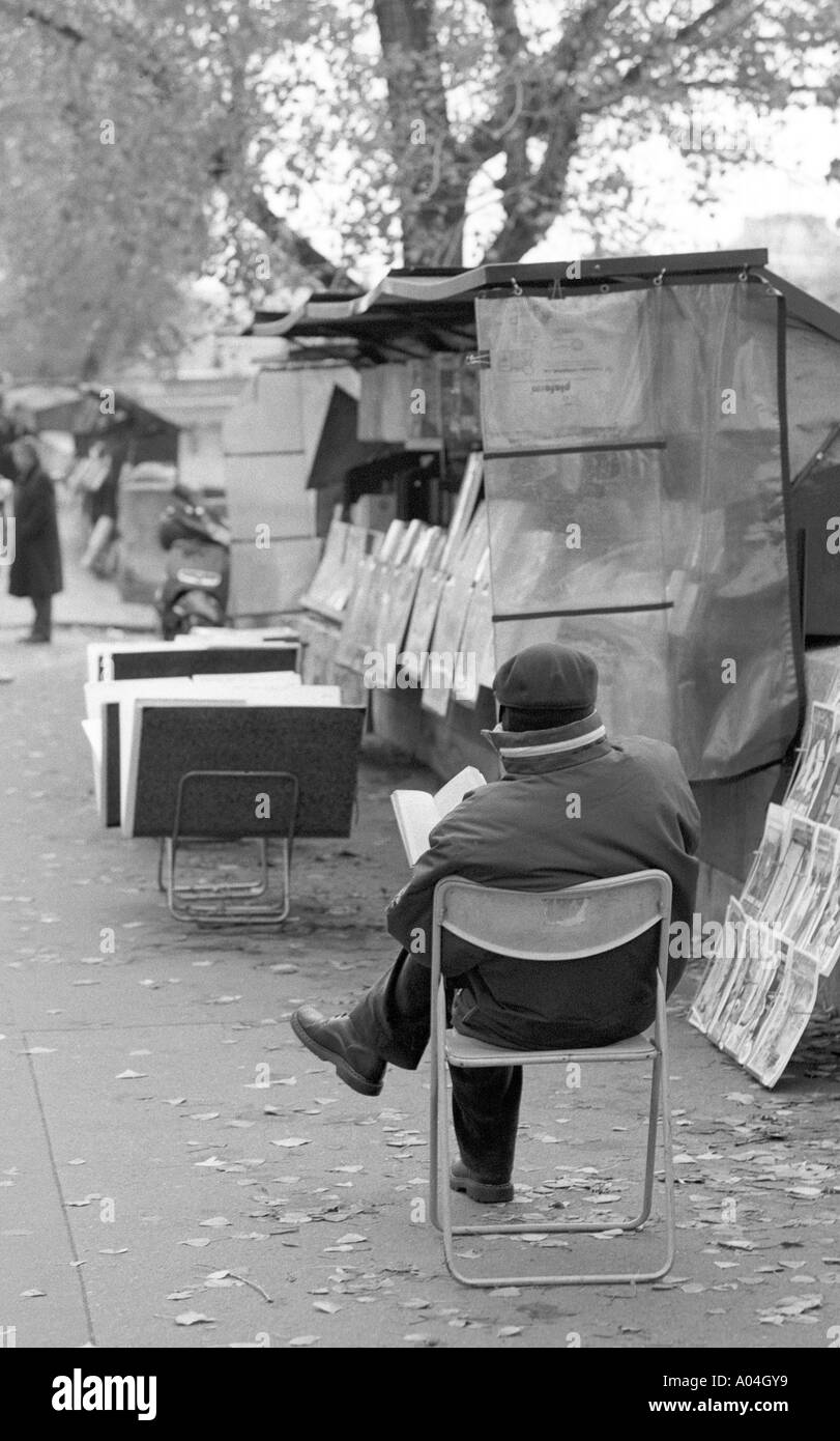 Parigi bookshop keeper la lettura di un libro sulla strada Foto Stock