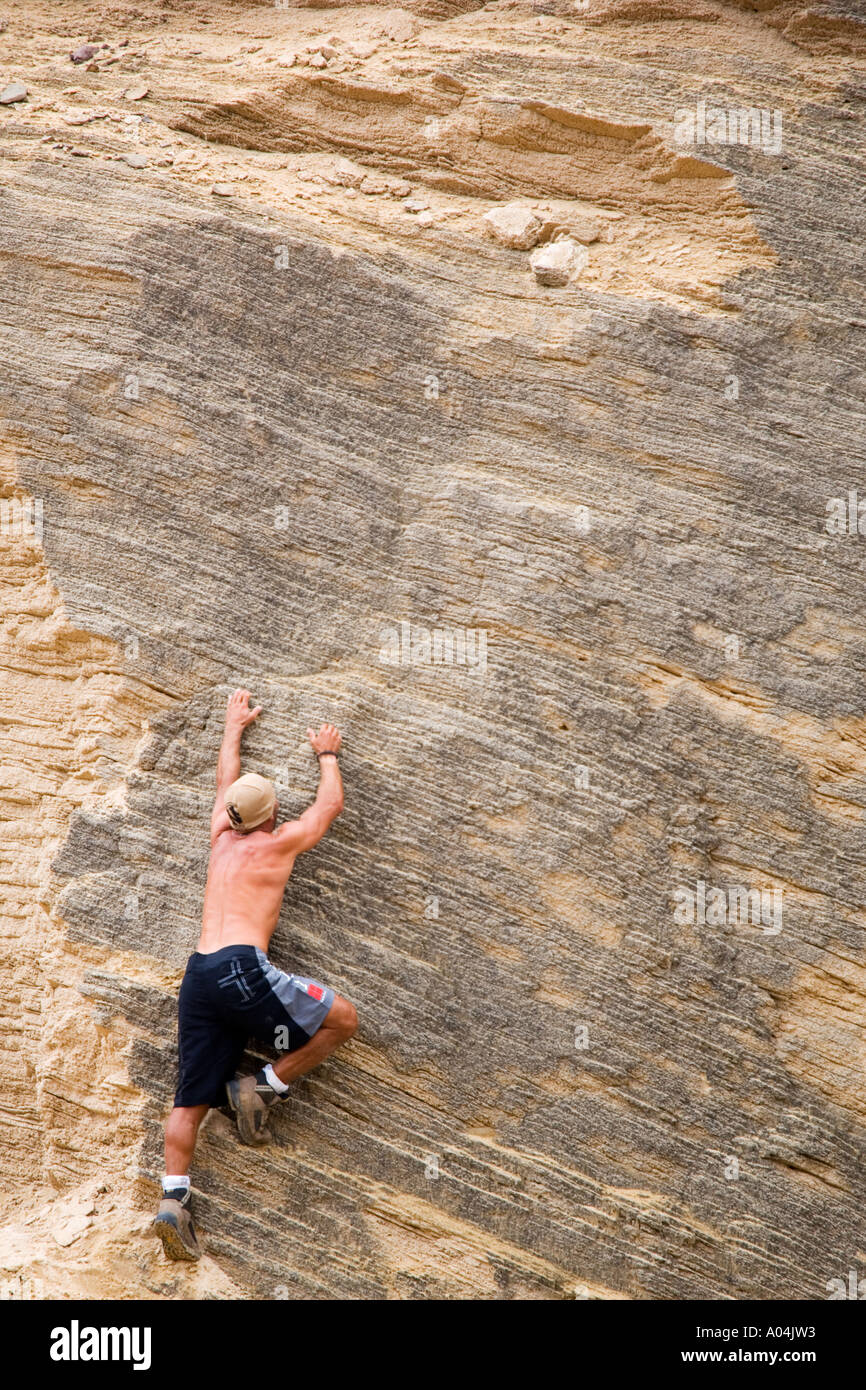 Immagine della vista posteriore di un uomo salendo una ben definita di beige e grigio colorato faccia rock Foto Stock