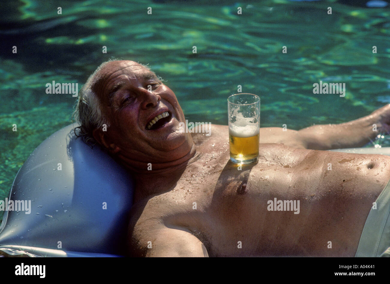 Rio de Janeiro, Brasile. Treno rapinatore Ronnie Biggs rilassarsi con una birra fresca in piscina nella sua casa di Santa Tereza nel 1990. Foto Stock