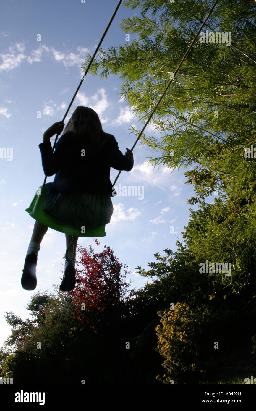 Silhouette di una ragazza su un giardino swing Foto Stock