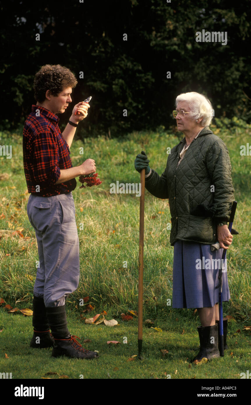 La vecchiaia titolare di pensione o di rendita il giardinaggio con maschio giovane giardiniere Inghilterra HOMER SYKES Foto Stock