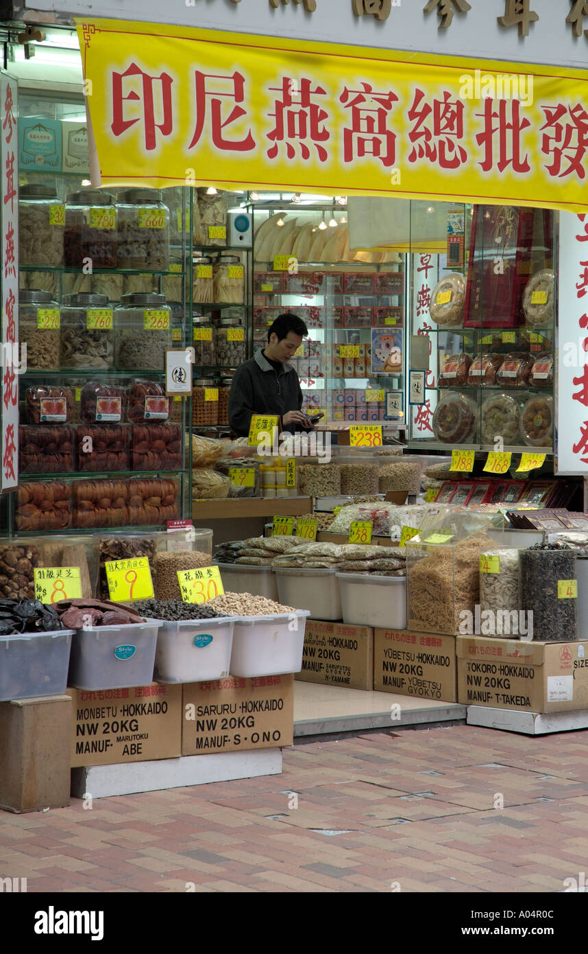 Dh Bonham Strand West Sheung Wan HONG KONG la medicina di erbe shop essiccato health foods negoziante utilizzando la calcolatrice cinese Foto Stock