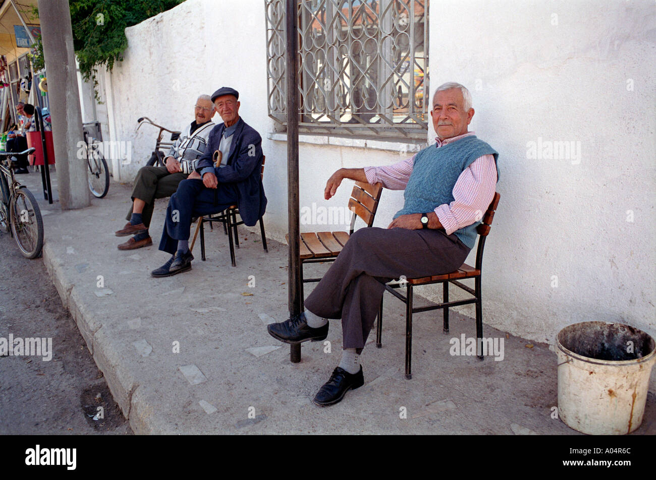 Un gruppo di uomini seduti e giocare bene un tradizionale gioco bere il tè e socializzazione sulla strada principale del piccolo villaggio rurale Foto Stock