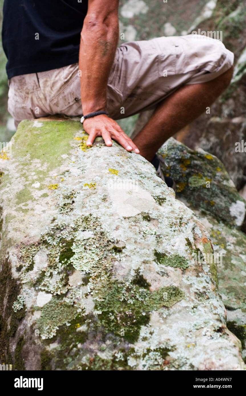 Ritagliato immagine della vista posteriore del modello da uomo seduto su di una roccia. Foto Stock