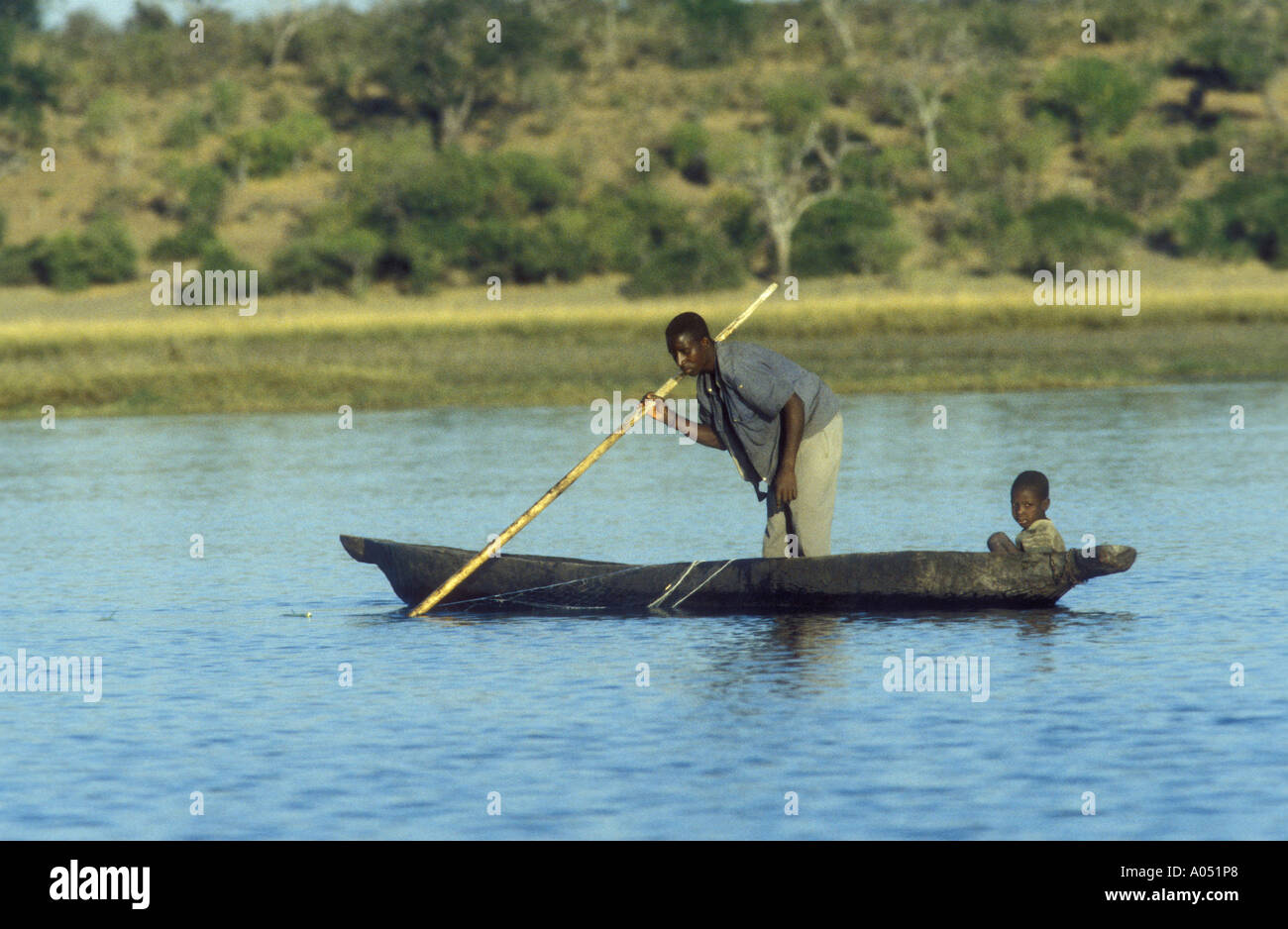Fisherman e piccolo ragazzo in una scavata canoa Chobe Caprivi strip sul confine fra il Botswana e lo Zimbabwe Foto Stock