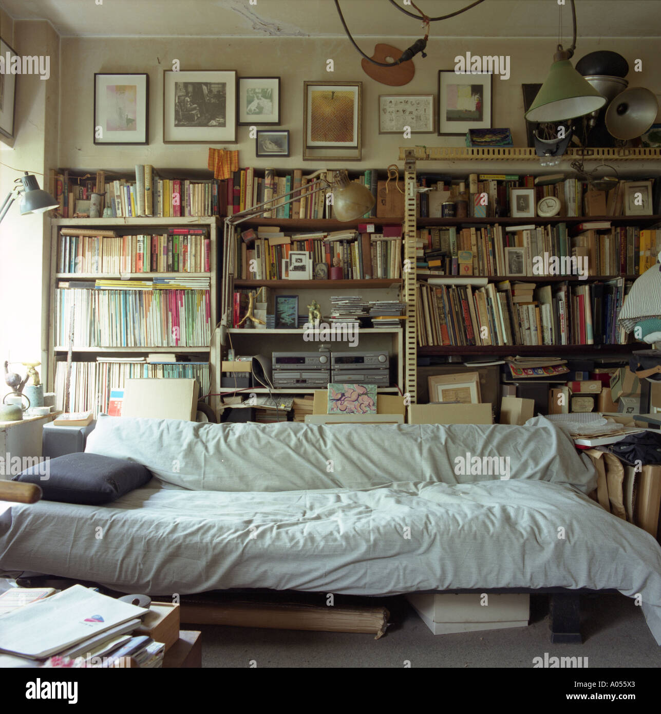 Divano letto in una stretta artista disordinato studio con scaffali pieni di  libri e di cose Foto stock - Alamy