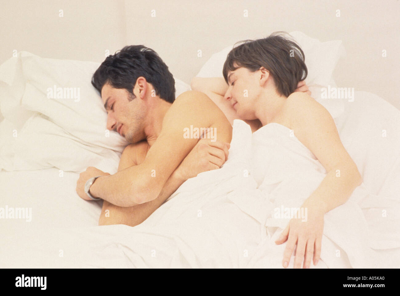 Giovane dormire nel loro letto stratificato con cuscini bianchi fogli e consolatore Foto Stock