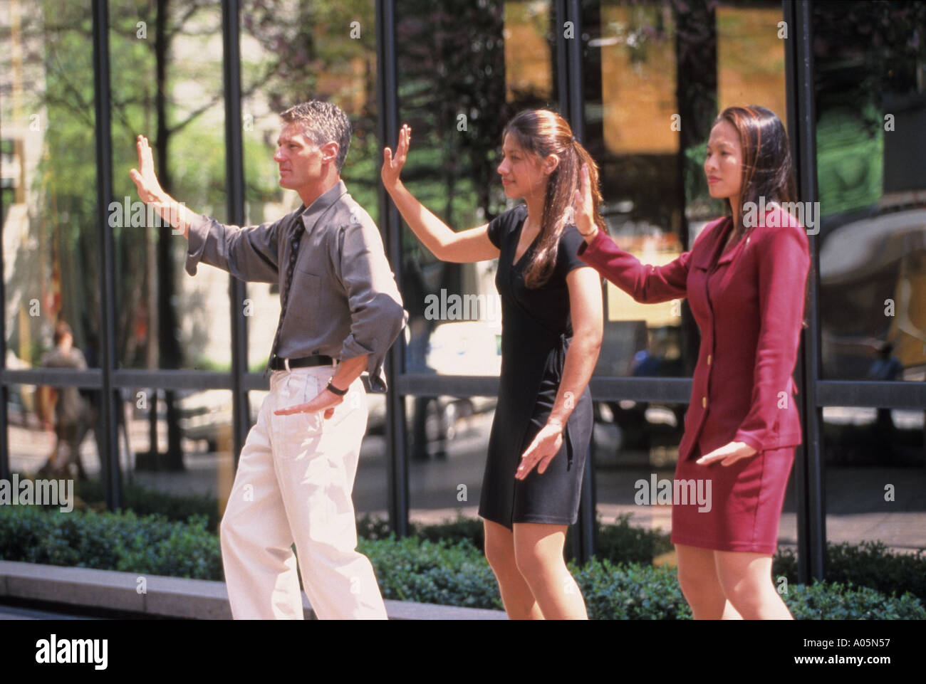 Due donne e un uomo di diversa etnia pratica Tai Chi arti marziali all'aperto mentre durante la pausa pranzo dal lavoro Foto Stock