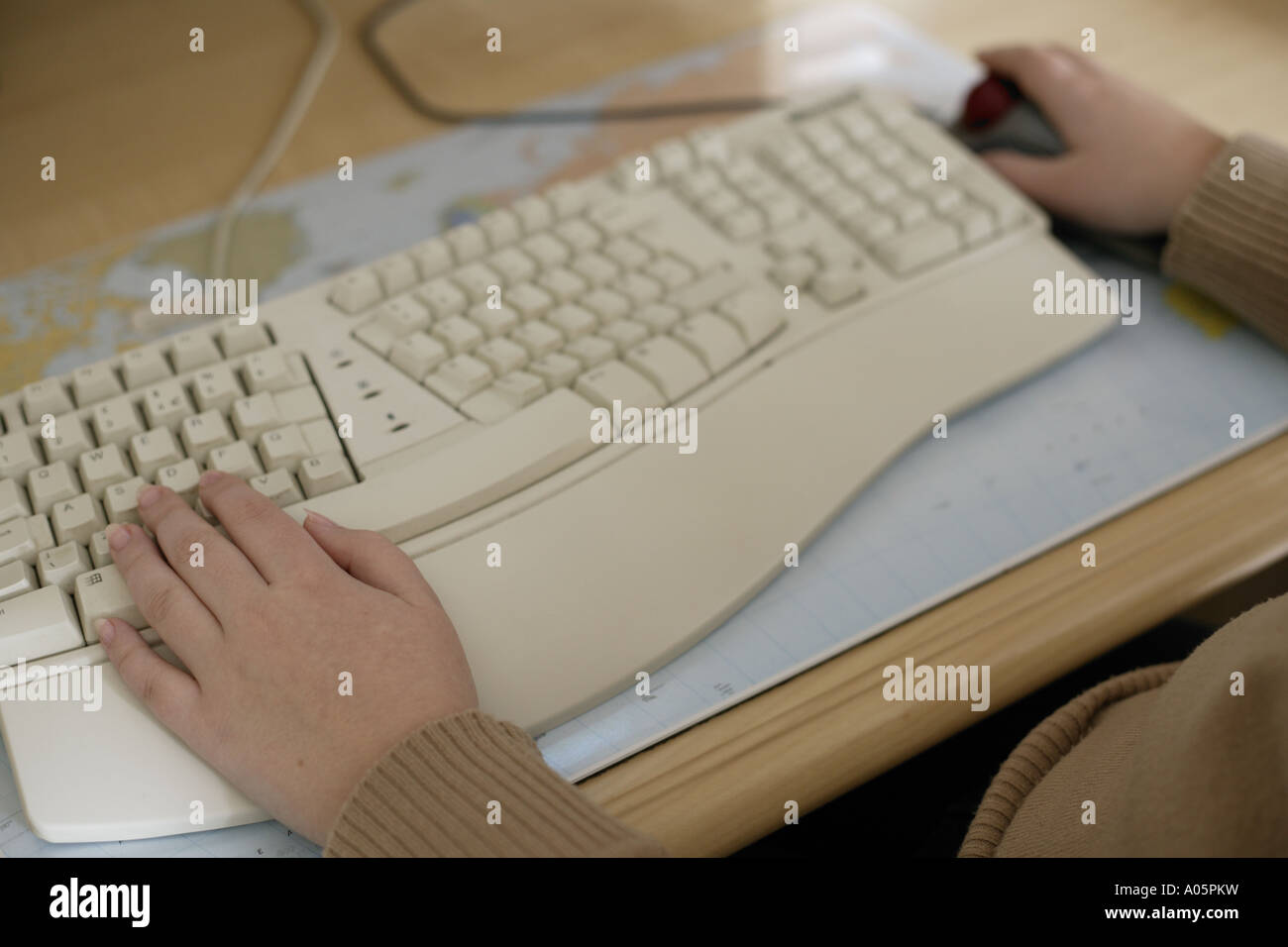 Le mani di una ragazza adolescente utilizzando una tastiera per PC & impilatrice mouse a sfera. Foto Stock