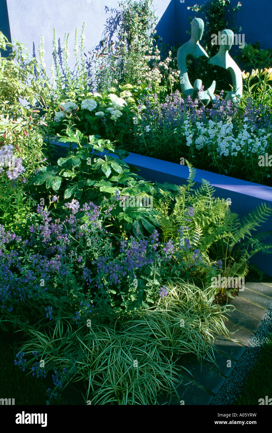 Scultura Moderna in giardino confine con nepeta e recinzione blu Foto Stock