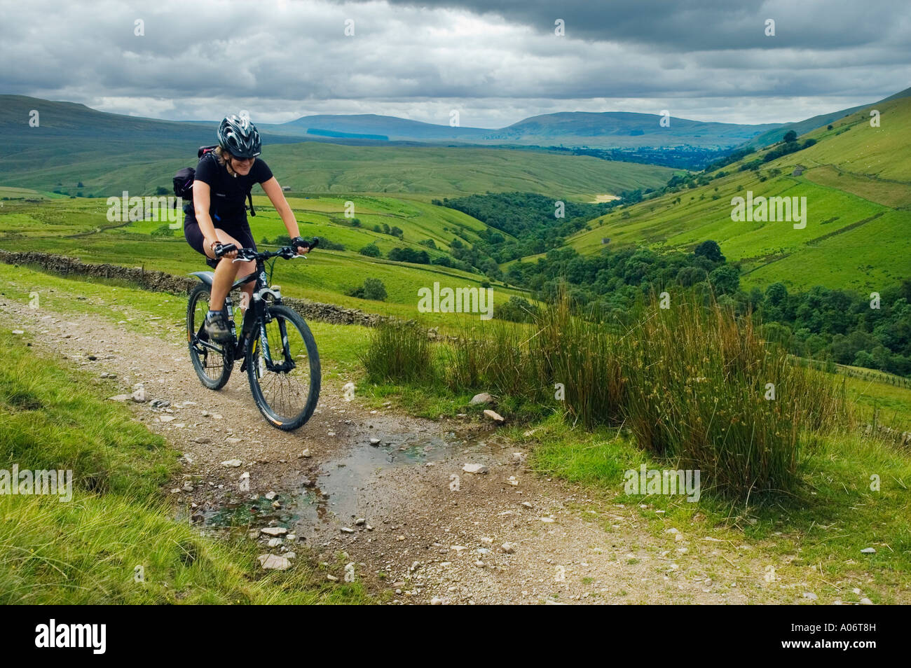 Femmina mountain biker su un cingolo sopra Wandale nel Howgill Fells in Cumbria Foto Stock
