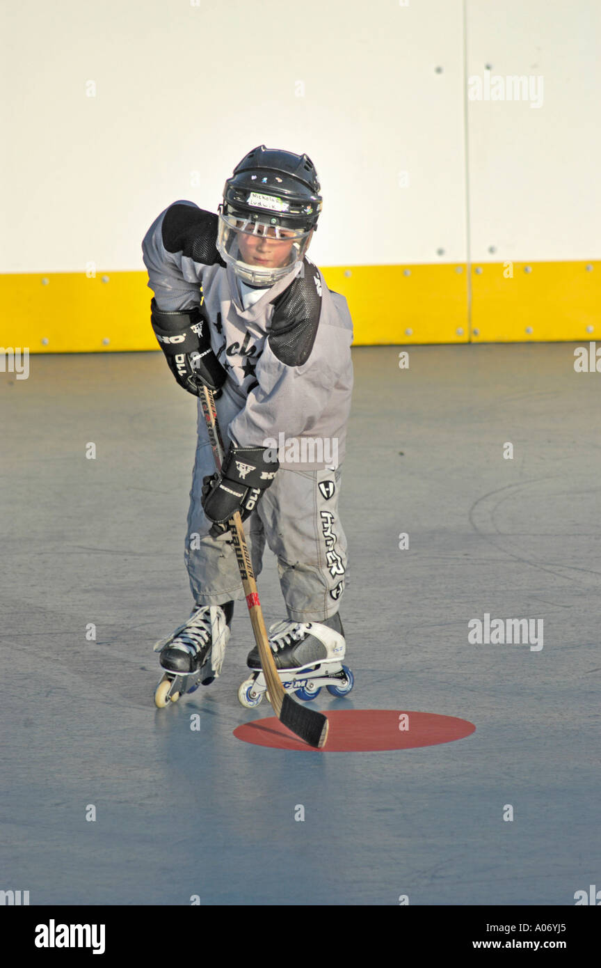 10 ragazzo di dieci anni durante la pratica con l'hockey a rulli squadra con attrezzatura di sicurezza completa sui pattini nella partita locale in estate e pullman Foto Stock