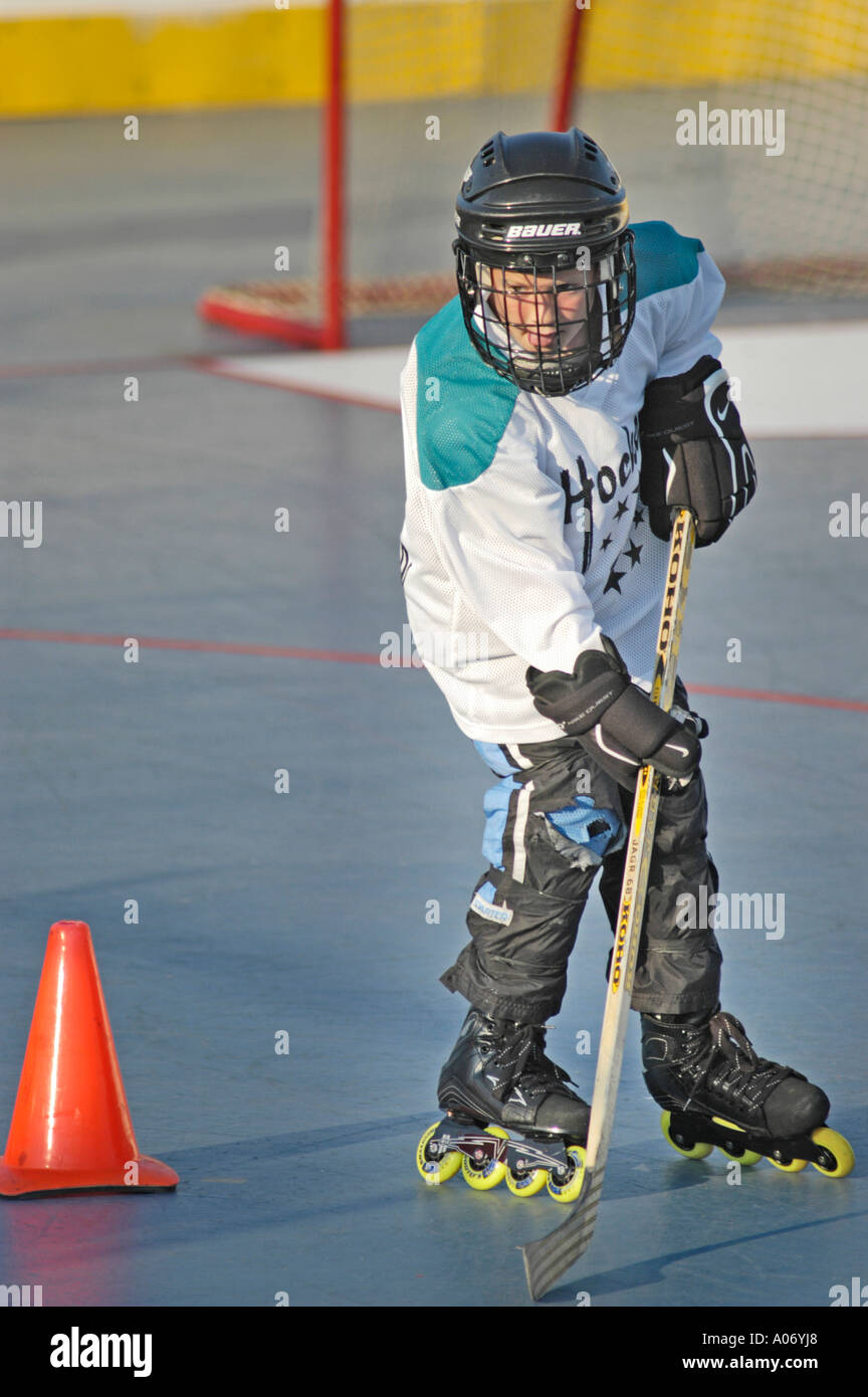 10 ragazzo di dieci anni durante la pratica con l'hockey a rulli squadra con attrezzatura di sicurezza completa sui pattini nella partita locale in estate e pullman Foto Stock