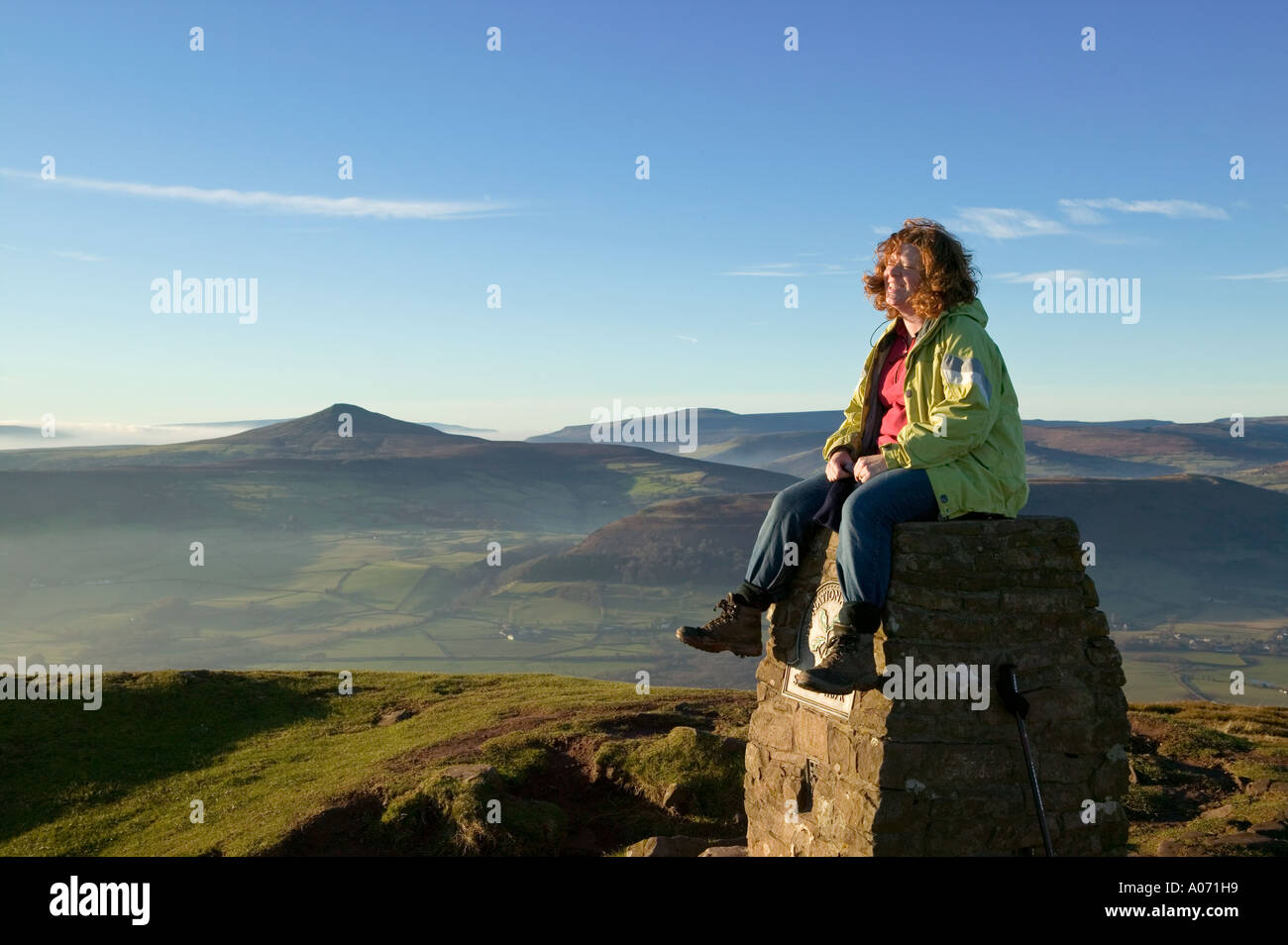 Escursionista femmina ridere mentre è seduto sul punto trig Skirrid Fawr Wales UK Foto Stock