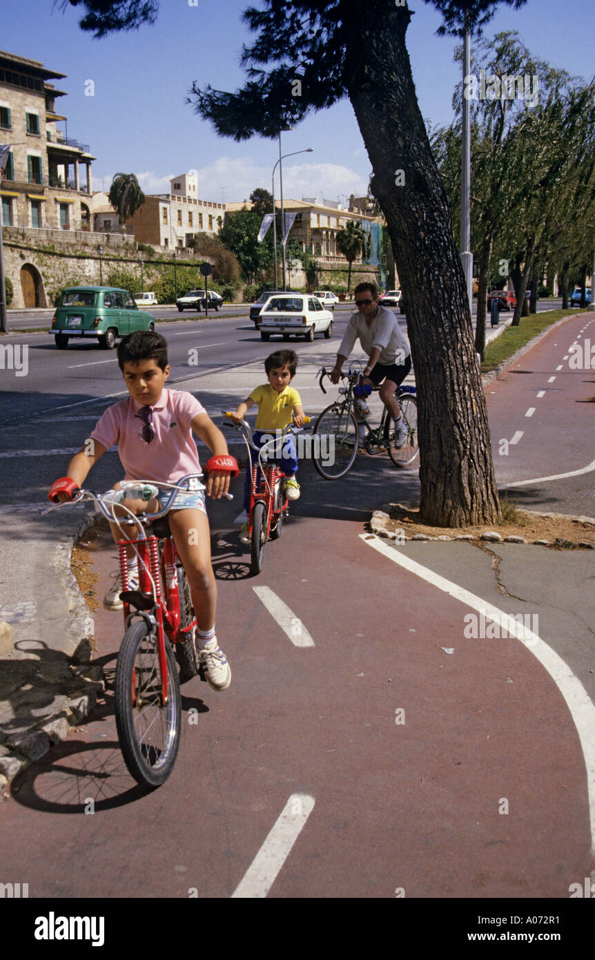 Bambini e adulti in bicicletta sul ciclo dedicato via a lato della strada trafficata Mallorca Spagna Europa Foto Stock