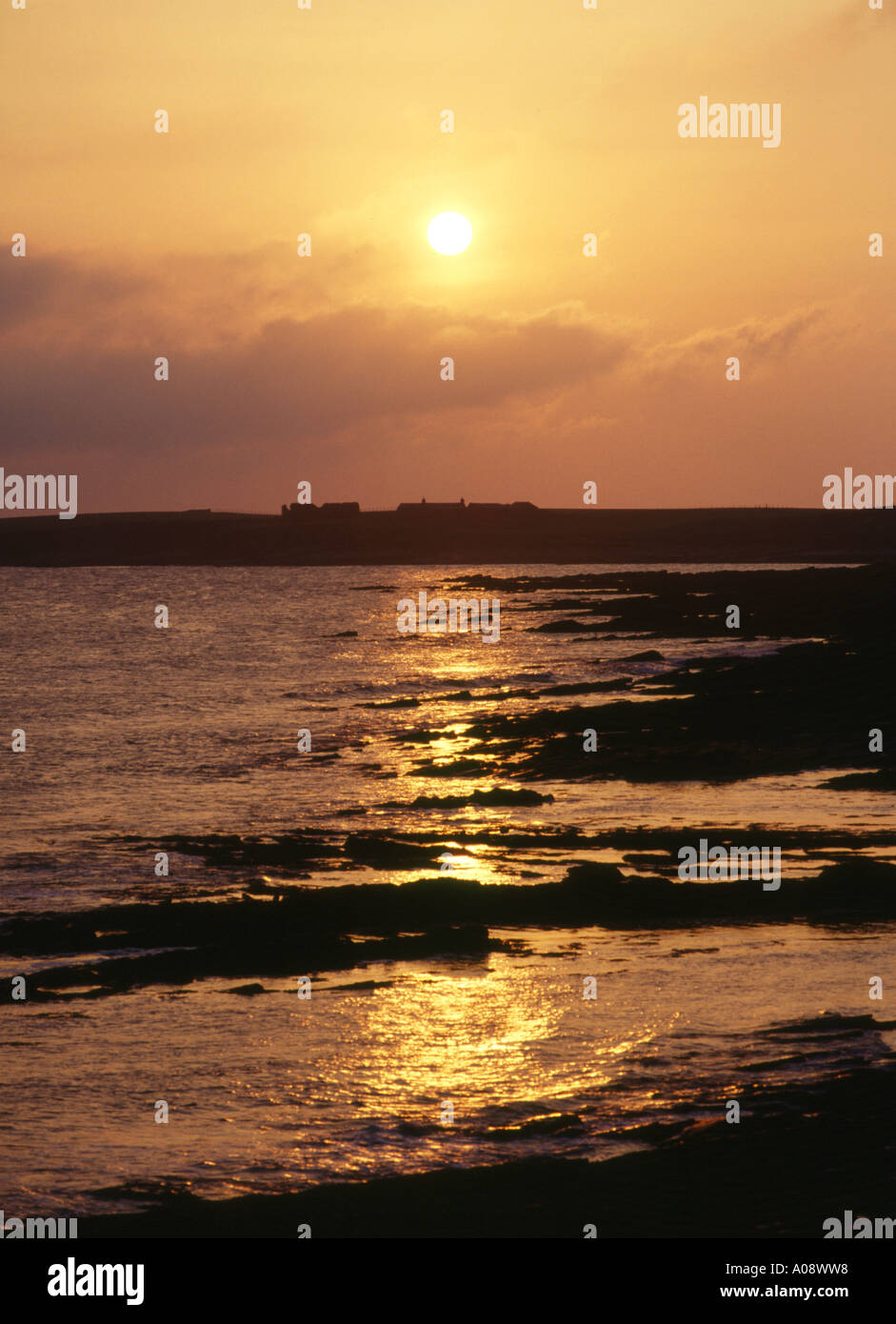 Dh spiaggia WARBETH ORKNEY Sunset over croft cottages promontorio roccioso bay shore Foto Stock
