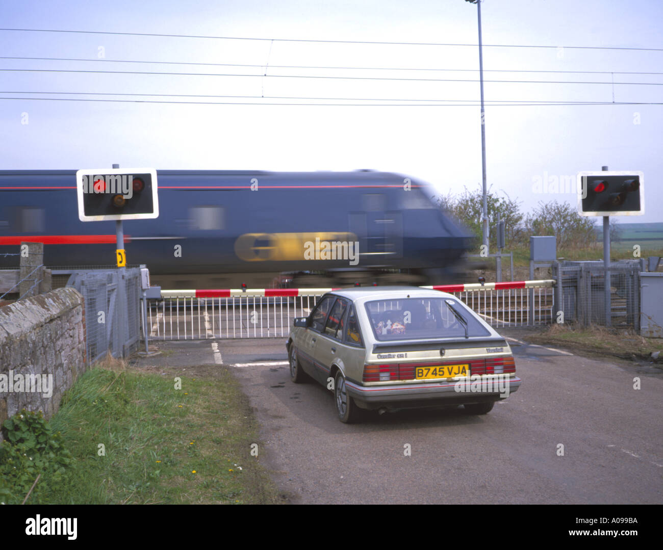 Automatic level crossing in una zona rurale e 225 treno Intercity, Northumberland, Inghilterra, Regno Unito. Foto Stock