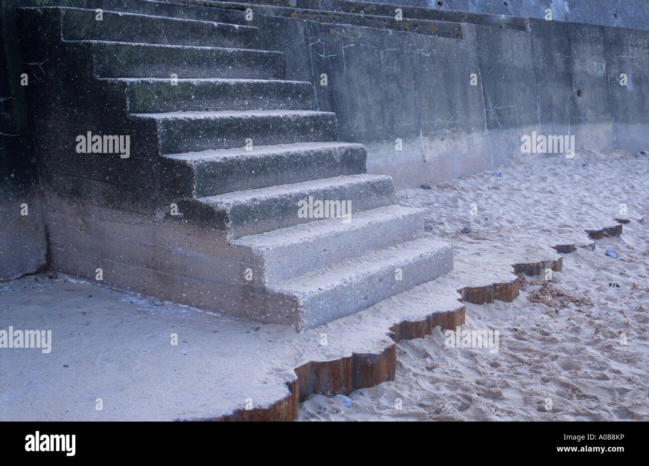 Esegui uno squat il volo di concreti passi dalla spiaggia di sabbia bianca a promenade sfigurato dalla brutale design e macchie e crepe Foto Stock