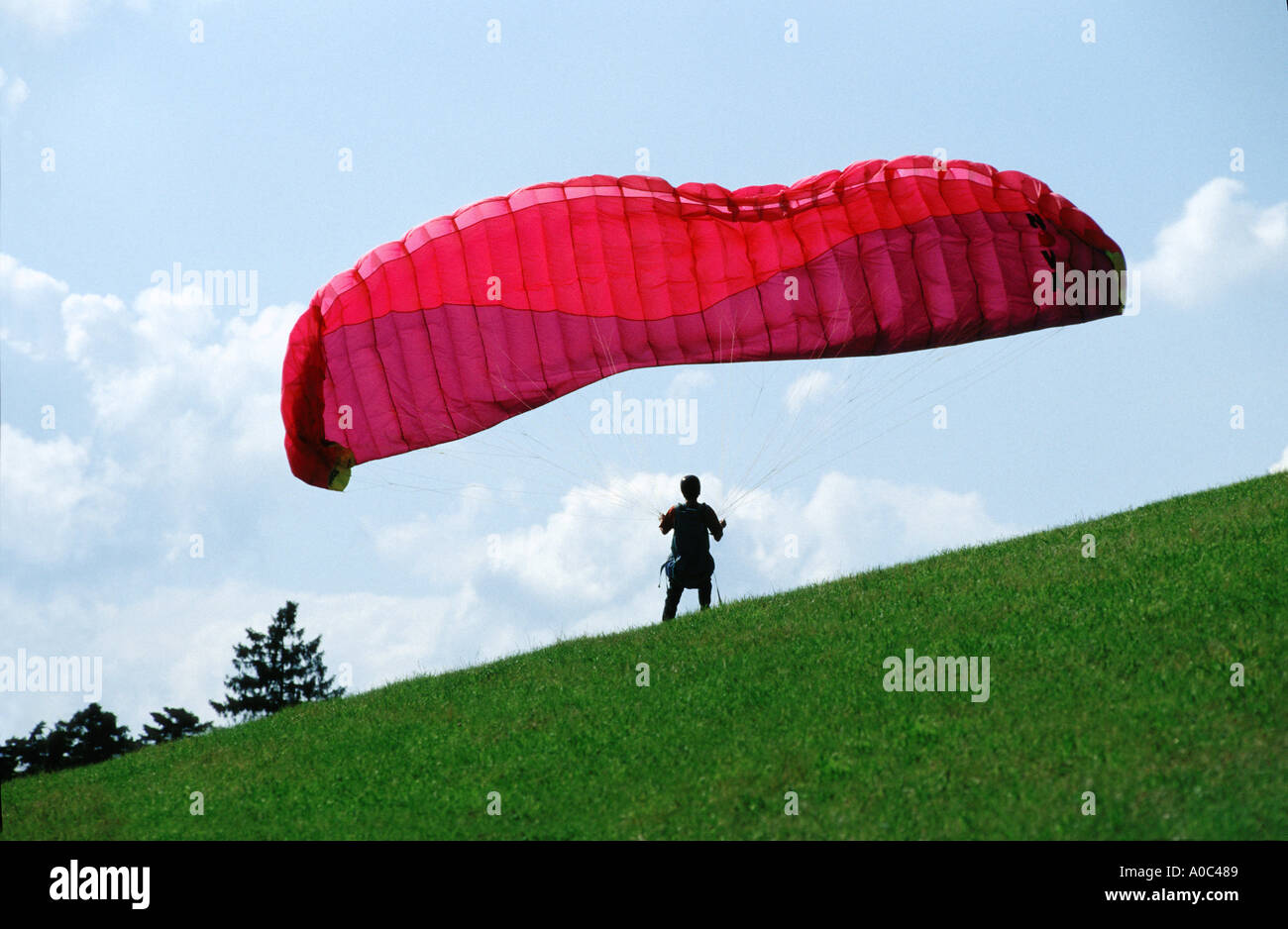 Deltaplano alianti su una collina di volo di colore colore rosso verde erba natura praticando sport tempo libero Foto Stock