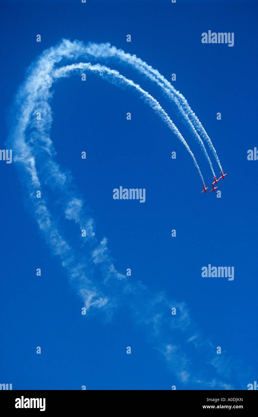 Quattro piccoli aerei rosso il loop il loop e finali e il fumo bianco contro il cielo blu chiaro Foto Stock