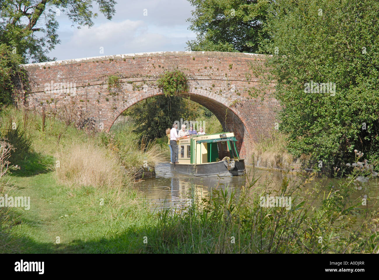 Famiglia godendo di giorno in giorno di noleggio barca, passando sotto il ponte sul Kennet & Avon canal in Witshire, England Regno Unito Foto Stock