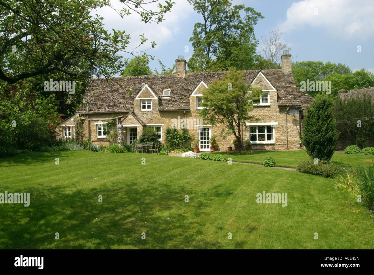 Piuttosto, ordinata cottage in pietra in un grande giardino erboso. Foto Stock