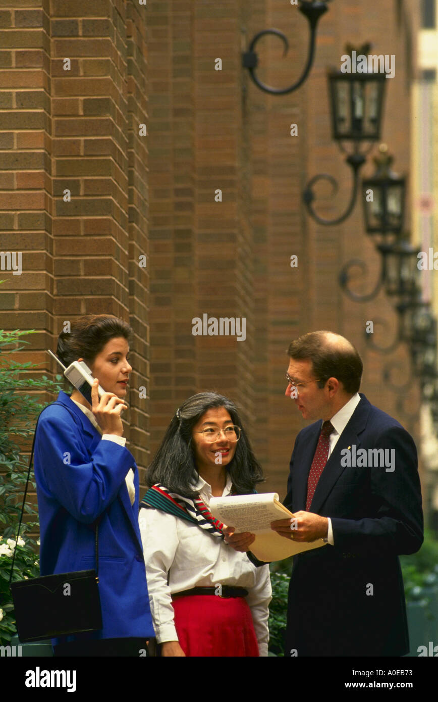 La gente di affari di soddisfare al di fuori ufficio edificio mentre la donna parla sul telefono cellulare Foto Stock
