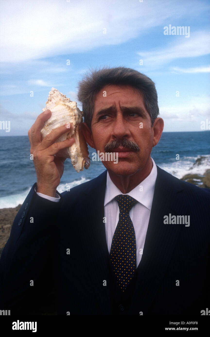 Un imprenditore ascolta una conchiglia di una nuova forma di comunicazione Foto Stock