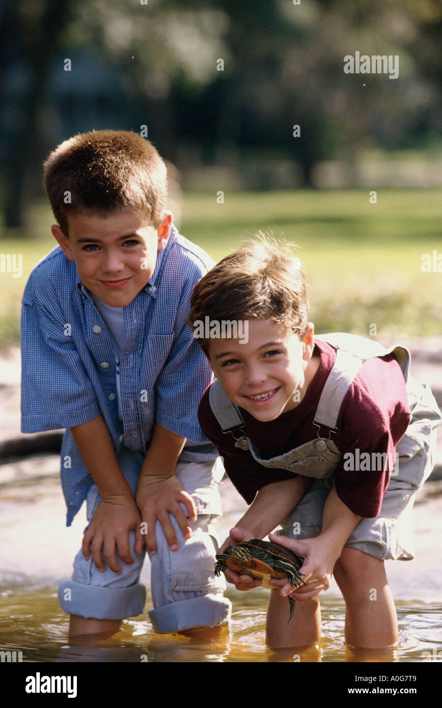 Ritratto di due ragazzi in piedi in acqua holding una tartaruga Foto Stock