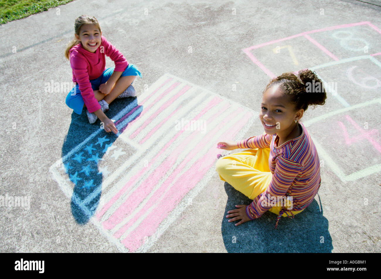 Ritratto di due ragazze disegno sul terreno con Chalk Foto Stock