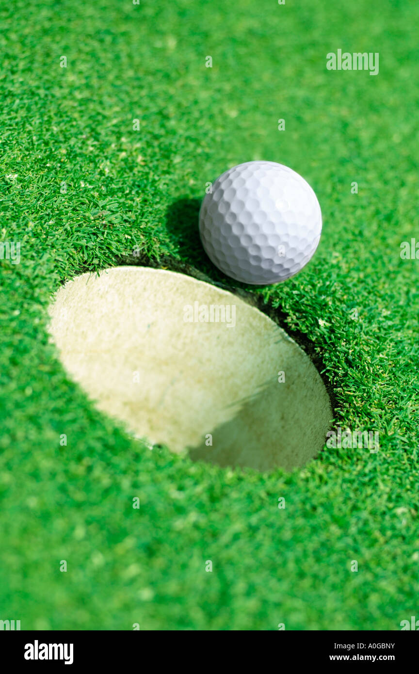 Palla da golf sul bordo del foro sul golf green Foto Stock