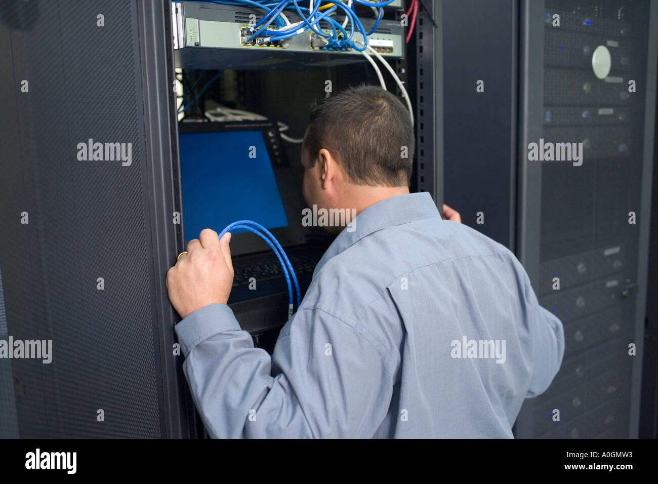 Vista posteriore di un tecnico guardando il monitor di un computer in una sala server Foto Stock