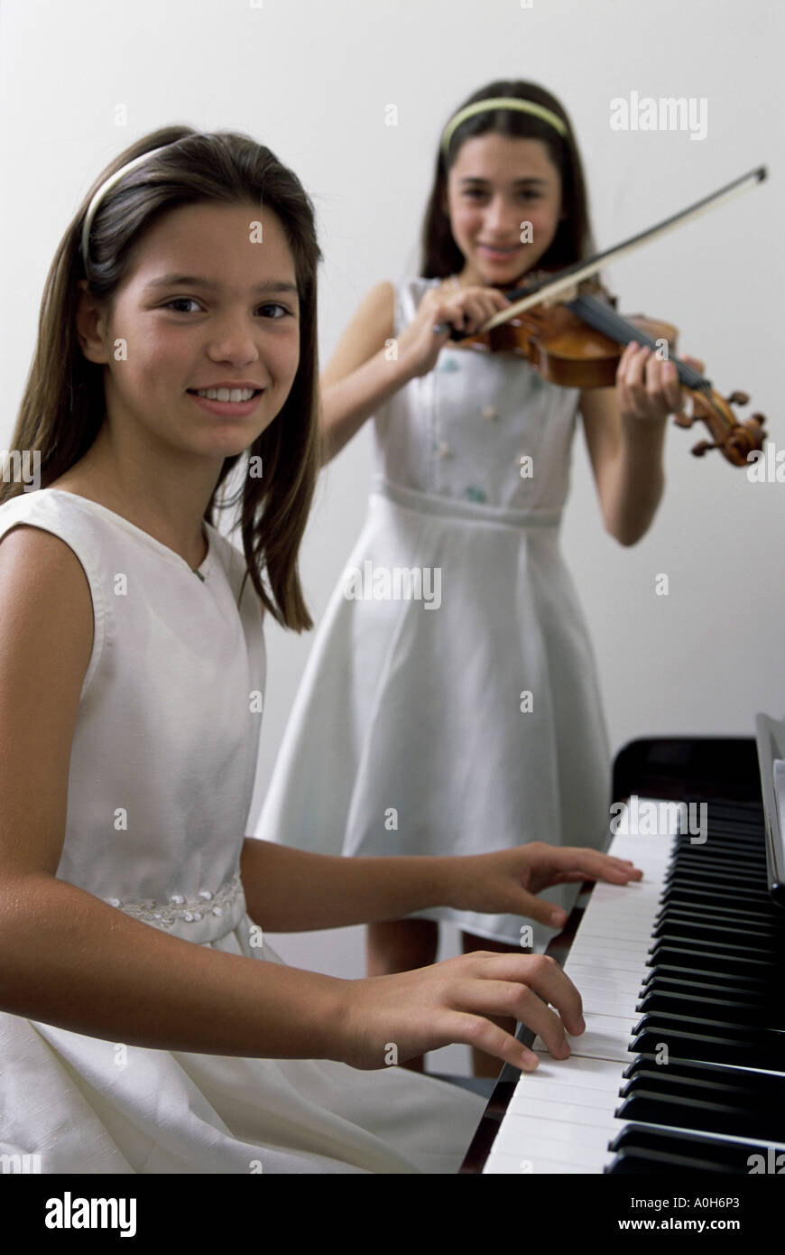 Ragazza suonare il pianoforte e un altro a suonare il violino Foto Stock