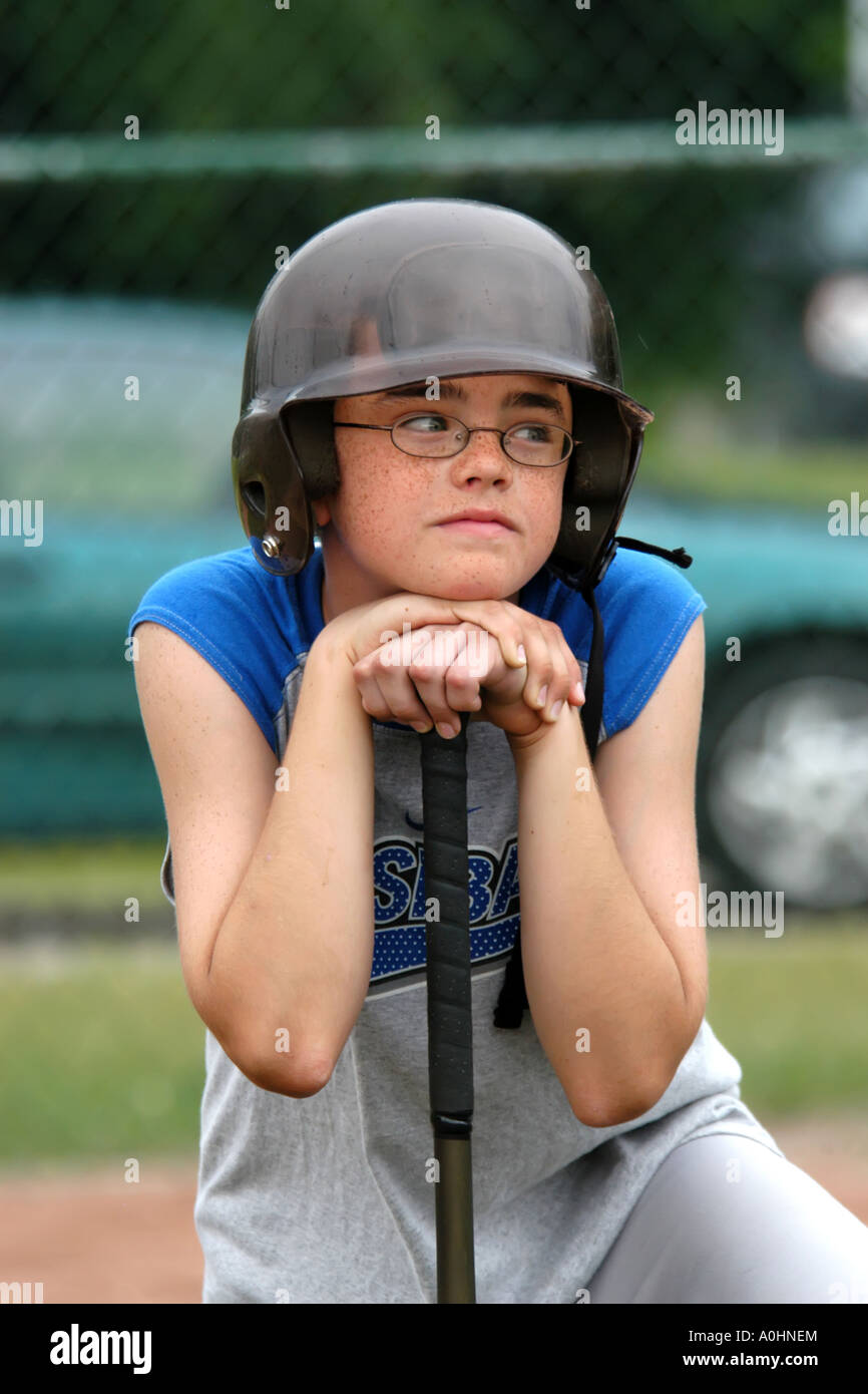 Ritratto di un ragazzo adolescente di prendere parte ad un softball practie sessione in Michigan che poggia il mento su una mazza da baseball Foto Stock