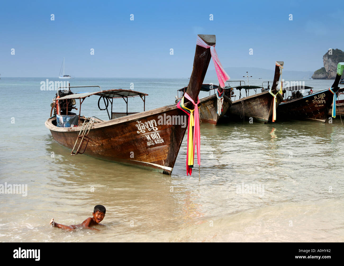 THA Thailandia Krabi Railay Beach long tail barche ragazzo giocando in acqua Foto Stock