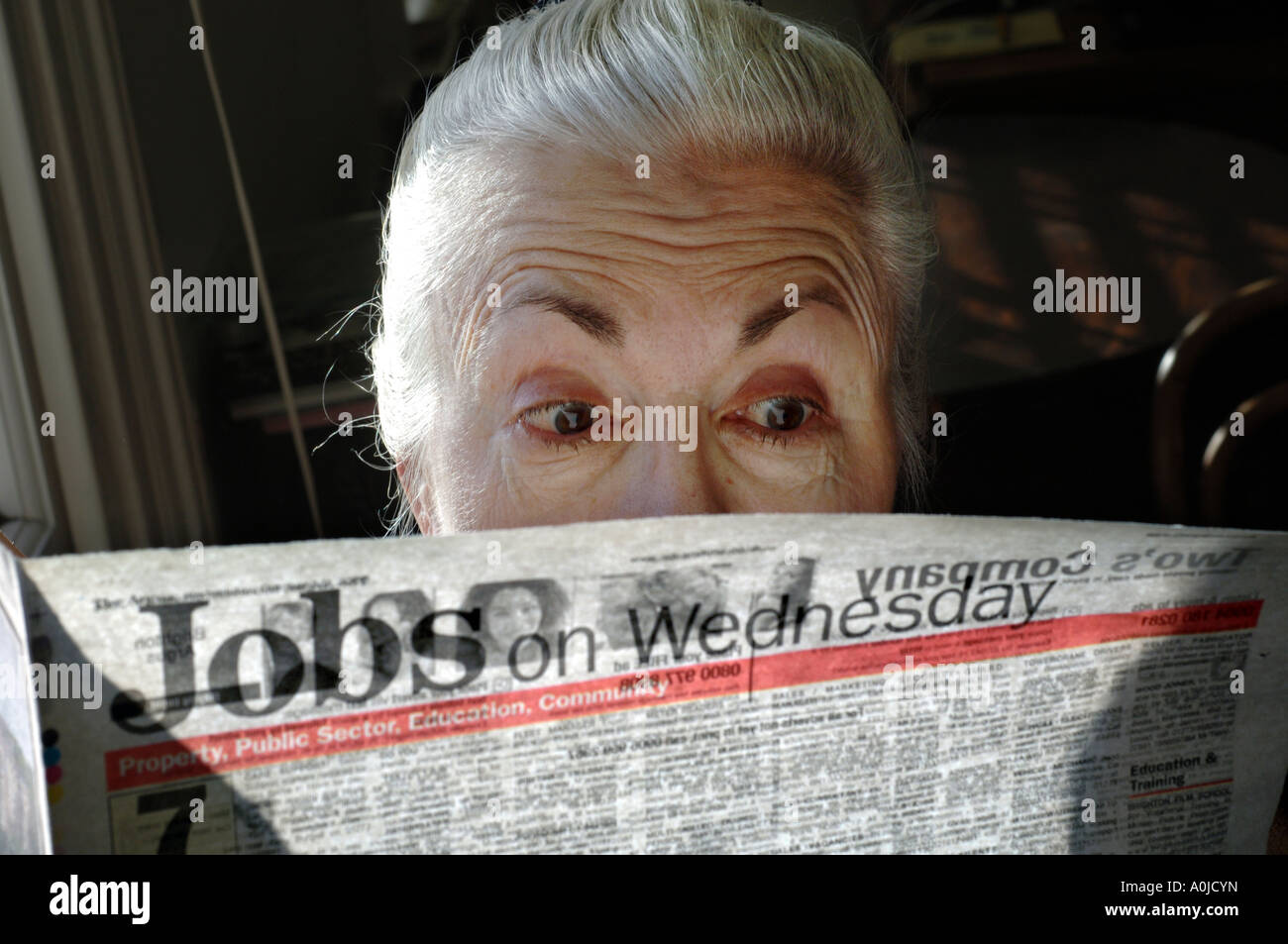 Un sorpreso cercando donna titolare di pensione o di rendita le indagini condotte sui posti di lavoro offerti nel suo giornale locale. Foto Stock