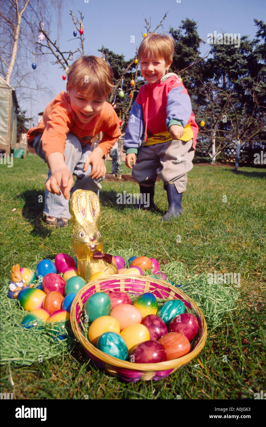 I bambini a giocare all'aperto nel giardino con dipinto di uova di Pasqua in un cestello Foto Stock