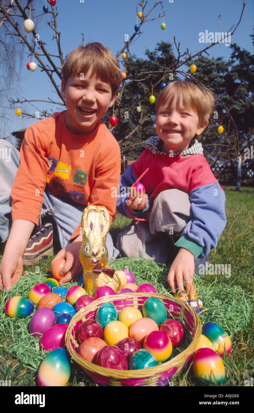 I bambini a giocare all'aperto nel giardino con dipinto di uova di Pasqua in un cestello Foto Stock