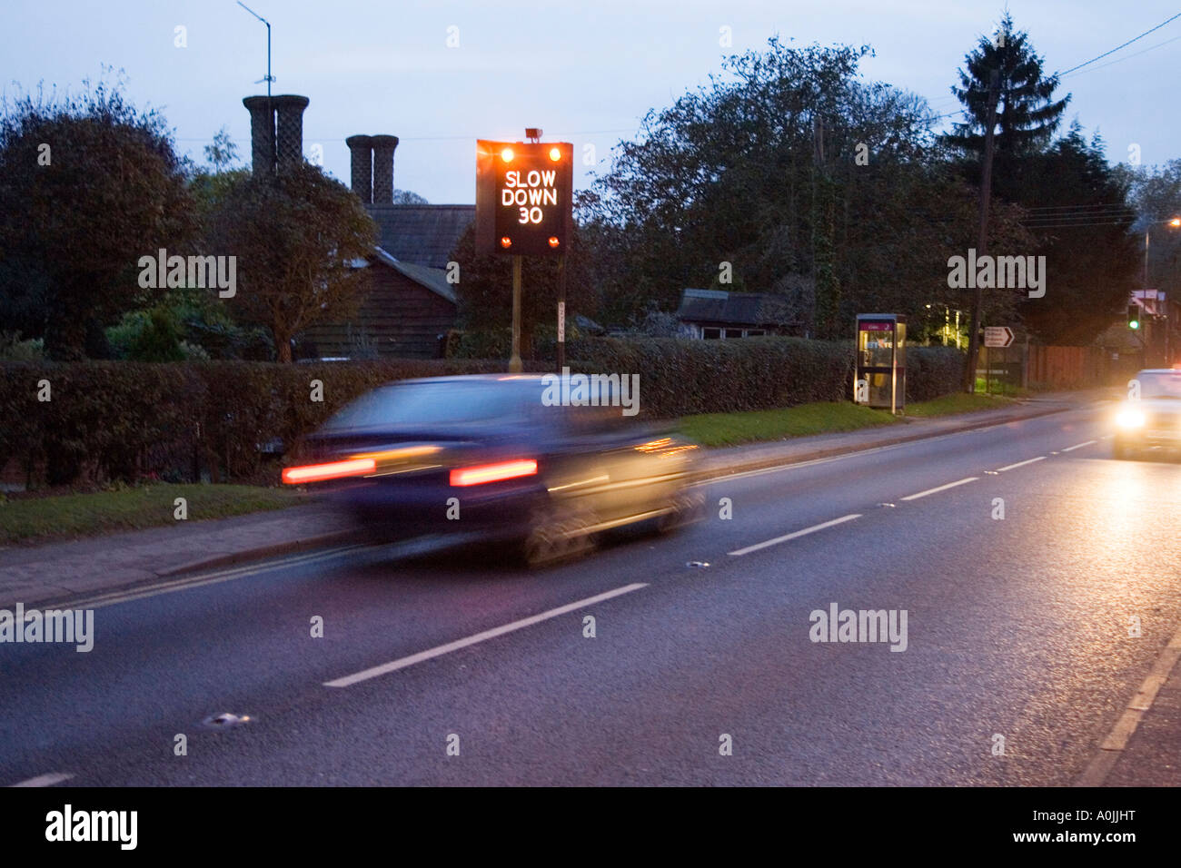 Un lampeggiante di avvertimento di velocità di segno e in rapido movimento di ora di punta il traffico attraverso il villaggio di Great Barton in Suffolk, Regno Unito Foto Stock Un lampeggiante di avvertimento di velocità di segno e in rapido movimento di ora di punta il traffico attraverso il villaggio di Great Barton in Suffolk, Regno Unito Foto Stock