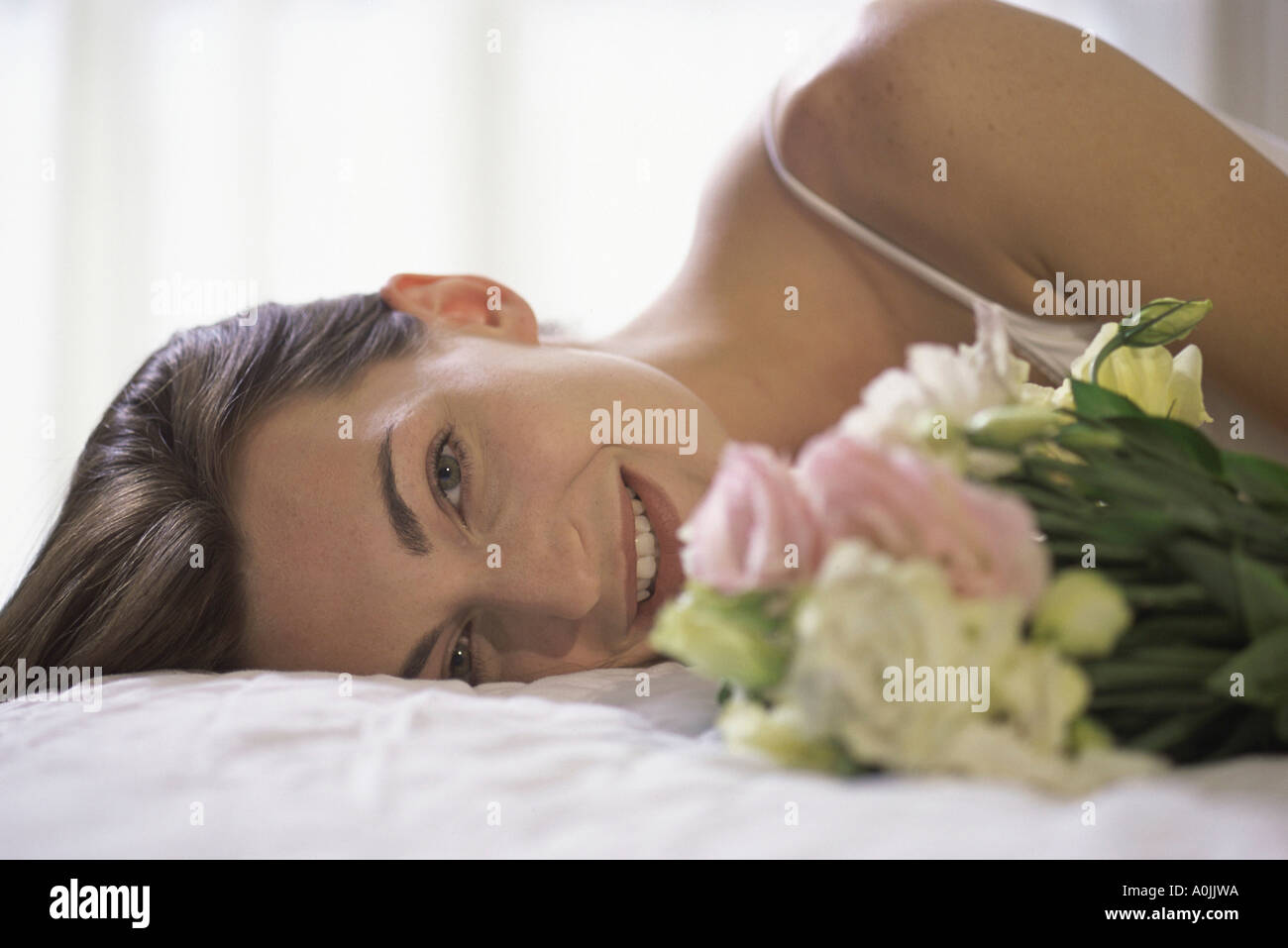 Ritratto di una giovane donna sdraiata tenendo un mazzo di fiori Foto Stock