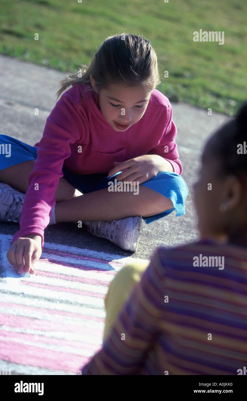 Angolo di alta vista di due ragazze di disegno con gesso sul pavimento Foto Stock
