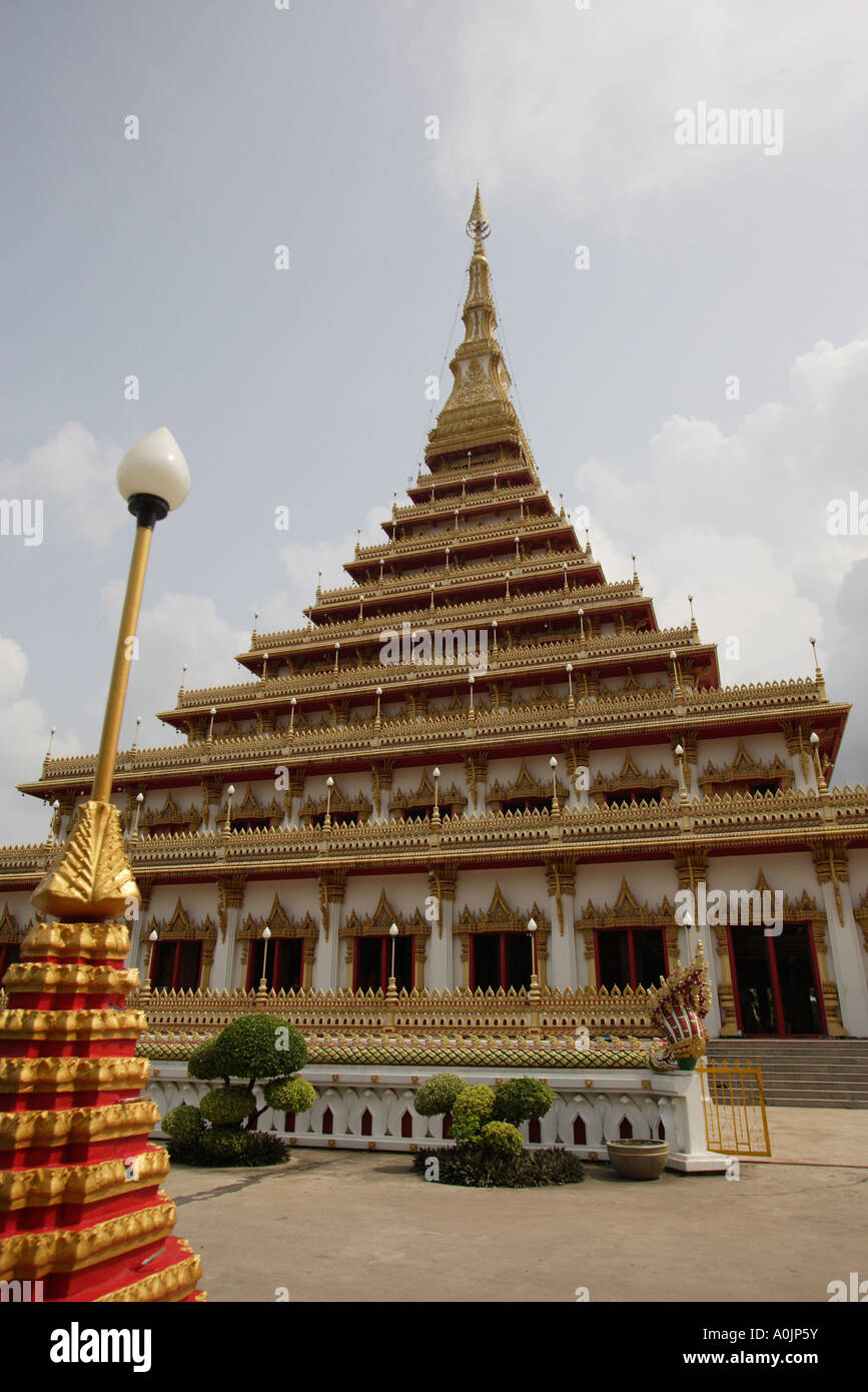 Ingresso anteriore della Wan di Nong Muang tempio il Chedi contro un pallido cielo blu in Khon Kaen un interessante rosso e oro a forma di cono di luce che si inclina verso destra a sinistra della foto Foto Stock
