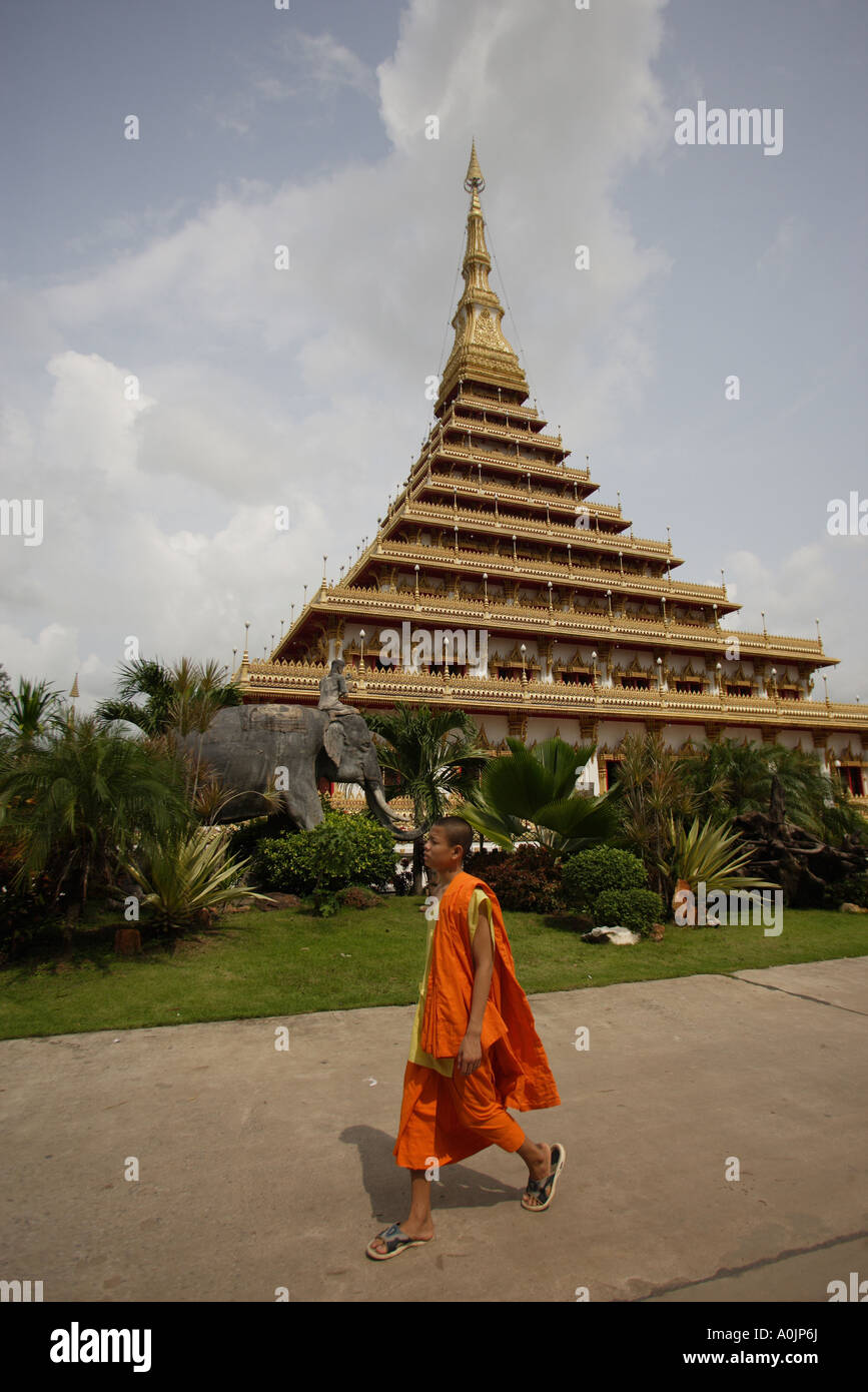 Ingresso anteriore della Wan di Nong Muang tempio il Chedi contro un pallido cielo blu in Khon Kaen statua dell'Elefante all'ingresso a sinistra della foto di un monaco in abiti dello zafferano passato a piedi Foto Stock