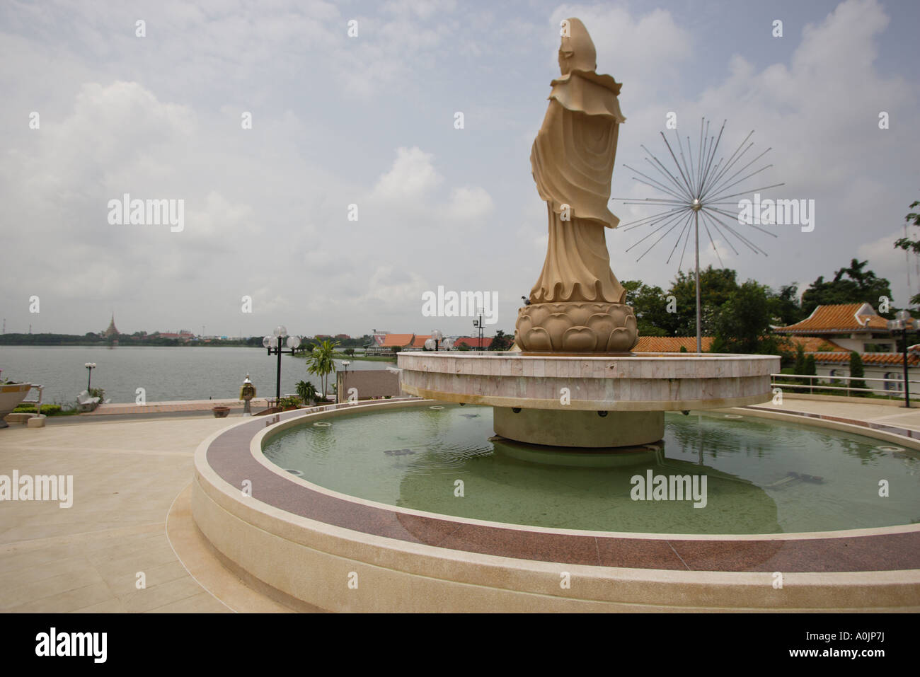 Statua al centro di una fontana di acqua al lago cittadino in Khon Kaen nella distanza può appena visto il chedi di Nong Muang Wan Foto Stock