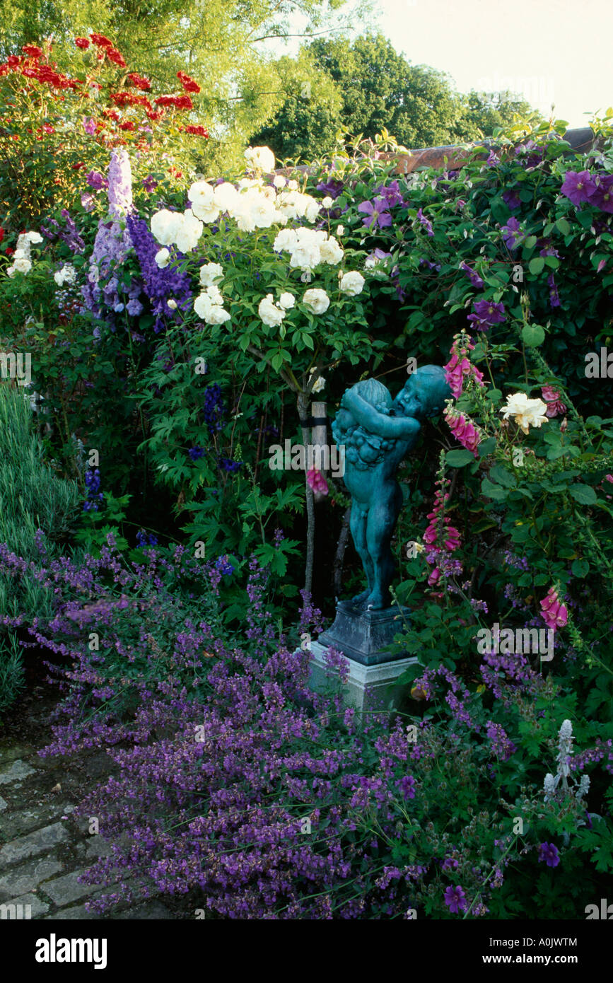 Statua in estate confine di rose e clematis contro la parete Foto Stock