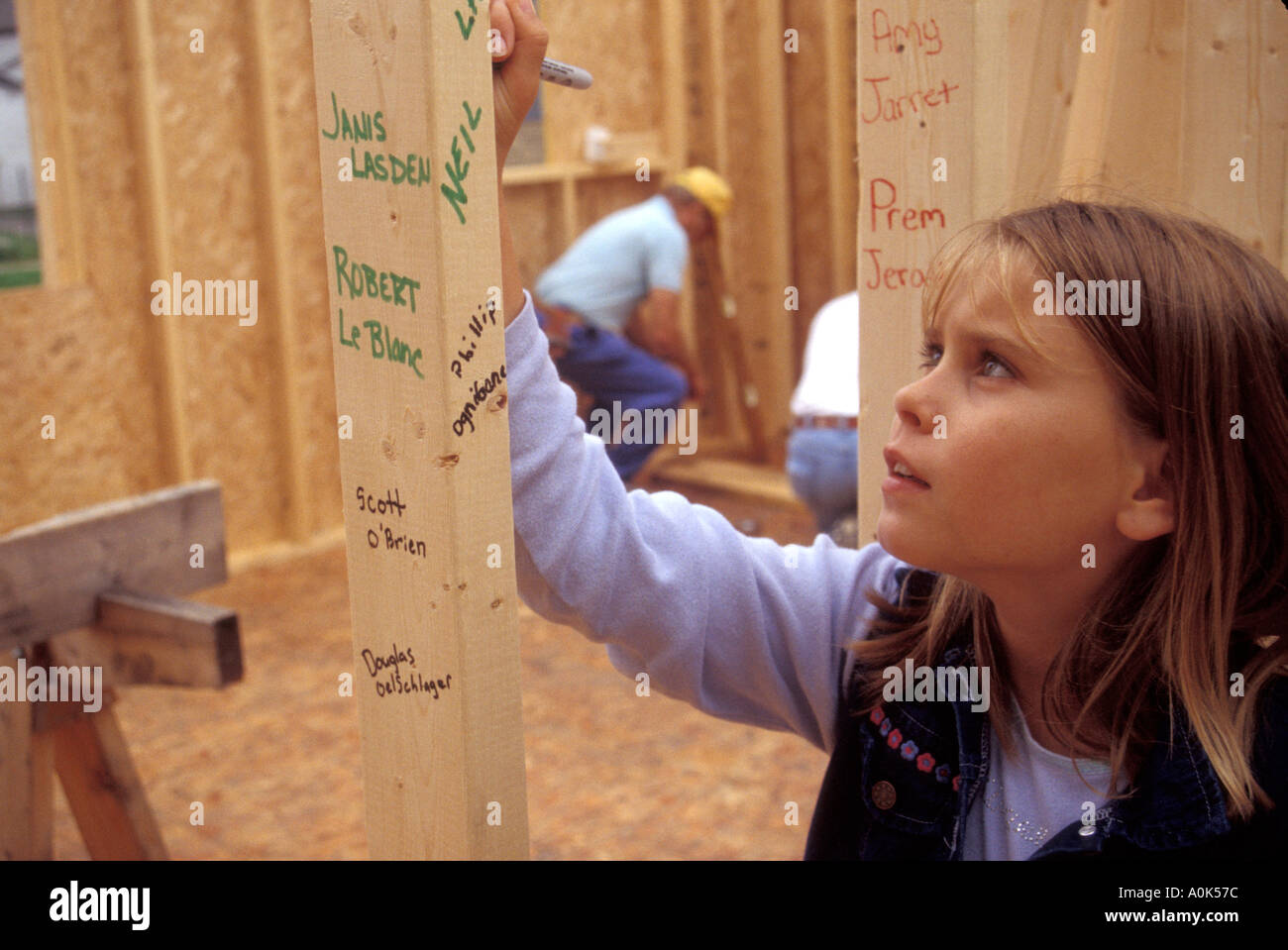 Una ragazza scrive i nomi di Settembre 11 vittime sui prigionieri di una casa in costruzione da Habitat for Humanity Foto Stock